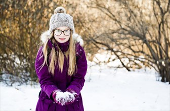 Caucasian girl holding snow in field