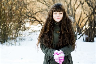 Caucasian girl holding snow in field
