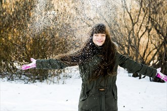 Caucasian girl throwing snow in field