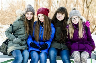Caucasian girls smiling on bench in winter