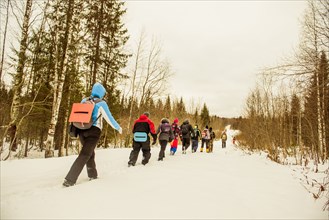 Caucasian hikers walking in a row on snowy path