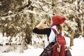 Caucasian woman photographing nature on snowy path