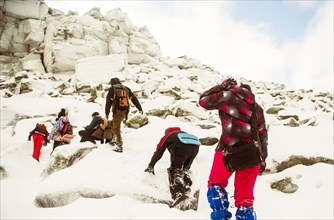 Caucasian hikers climbing snowy rock formations