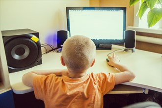 Caucasian boy using computer at desk