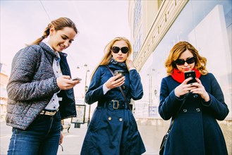 Caucasian women using cell phones in city