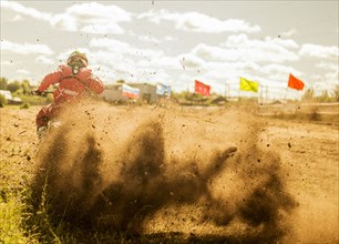 Caucasian motocross biker spraying dirt on race course