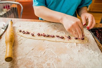 Caucasian woman placing berries in dough