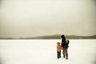 Caucasian father and son walking in snowy remote field