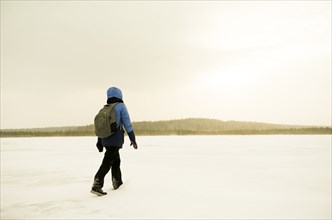 Caucasian hiker walking in snowy remote field