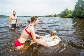 Caucasian family swimming in lake