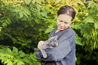 Caucasian woman petting cat in garden