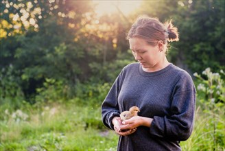Caucasian woman holding chick in garden