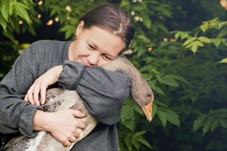 Caucasian farmer hugging goose in garden