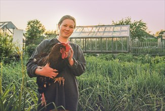 Caucasian farmer holding chicken in garden
