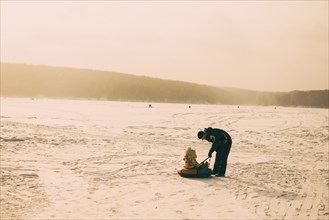 Caucasian father and daughter playing in snowy field