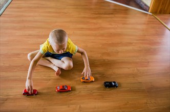 Caucasian boy playing with toy cars on floor