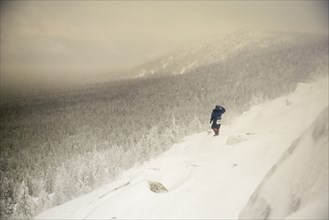 Caucasian hiker waking on snowy hillside