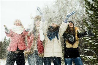 Caucasian girls tossing snow in air