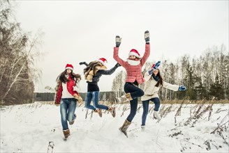Caucasian girls jumping for joy in snow