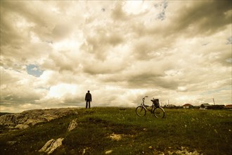 Caucasian man with bicycle in field