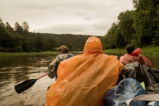People wearing ponchos on boat in river
