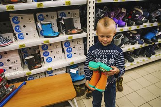 Caucasian boy admiring boots in store