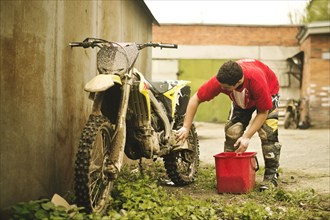 Caucasian man washing dirt bike