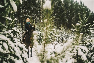 Caucasian woman riding horse in snowy forest