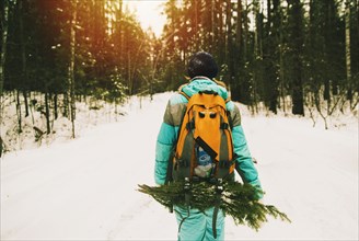 Caucasian hiker carrying branches in snowy forest