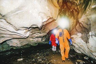 Caucasian hikers wearing headlamps in cave