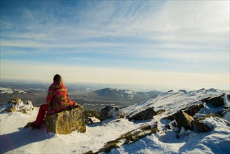 Woman hiker sitting on mountain rock in winter