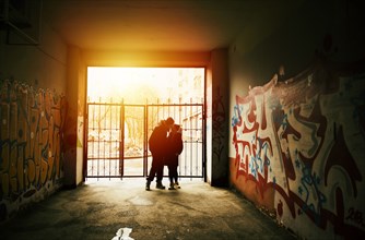 Couple kissing near graffiti at urban gate