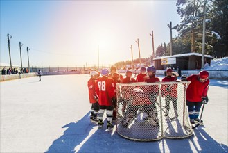 Caucasian boys surrounding goalie in ice hockey outdoors