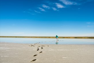 Footprints of woman wearing backpack on beach