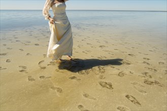 Footprints of bride wading in ocean at beach