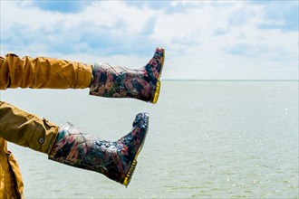 Person wearing boots on hands over water