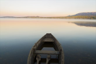 Empty rowboat on lake at sunset