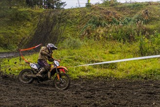 Caucasian racer on motorcycle spraying dirt