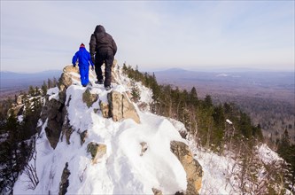 Caucasian men hiking on mountain in winter