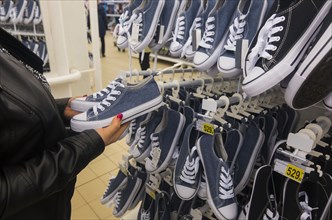 Hands of Caucasian woman holding sneakers in store