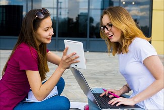 Caucasian women using laptop and digital tablet outdoors