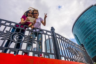 Caucasian women posing for selfie near railing using digital tablet