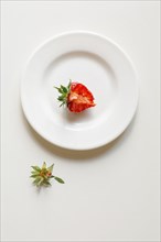 Bitten strawberry on white plate