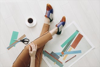 Legs of woman designer sitting on floor wearing multicolor shoes