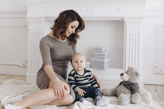 Caucasian mother sitting on floor with baby son