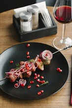 Meat on skewer with pomegranate seeds and red wine