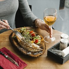 Woman eating fish with white wine