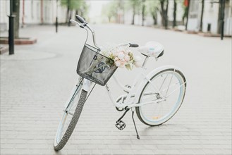 White bicycle on street with flowers in basket