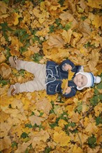 Middle Eastern baby boy laying in autumn leaves