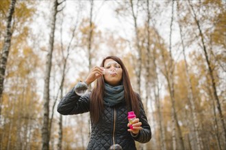 Middle Eastern woman blowing bubbles in autumn